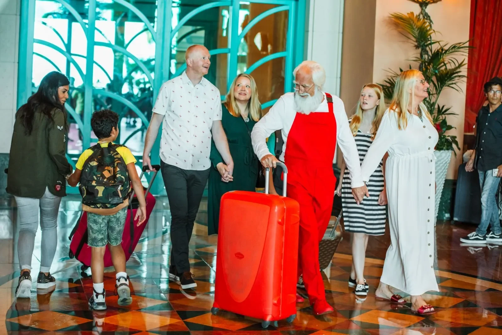 Una familia con niños y maletas cruza el vestíbulo de un hotel hacia recepción