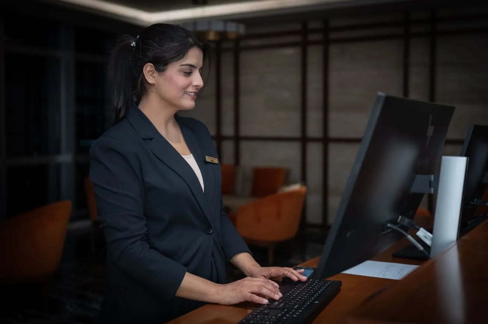 Una recepcionista trabaja con el ordenador en el mostrador de un hotel